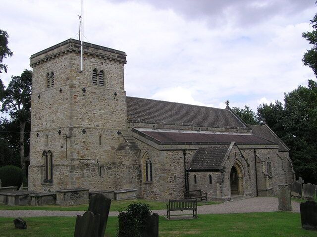 A stone church with a bell tower and a graveyard.