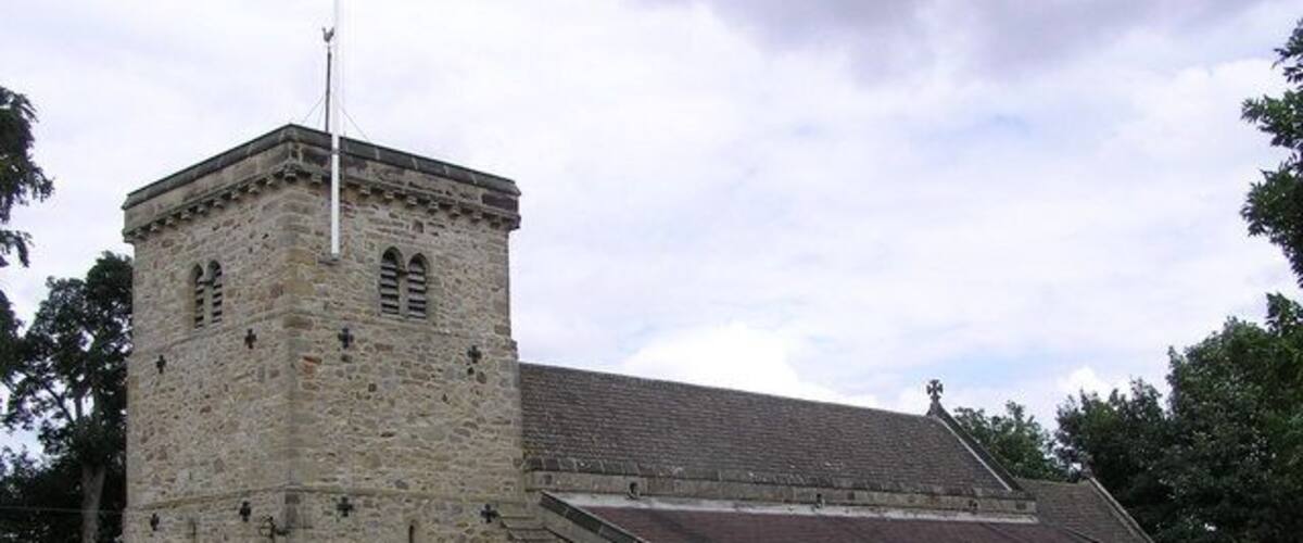 A stone church with a bell tower and a graveyard.