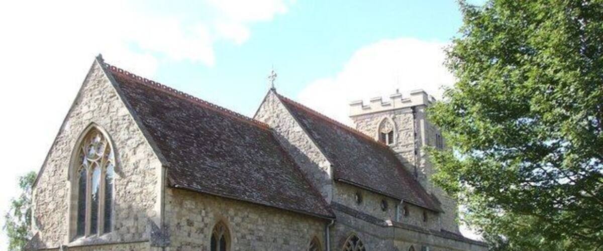 A historic stone church with a steeply pitched roof, arched windows, and a bell tower.