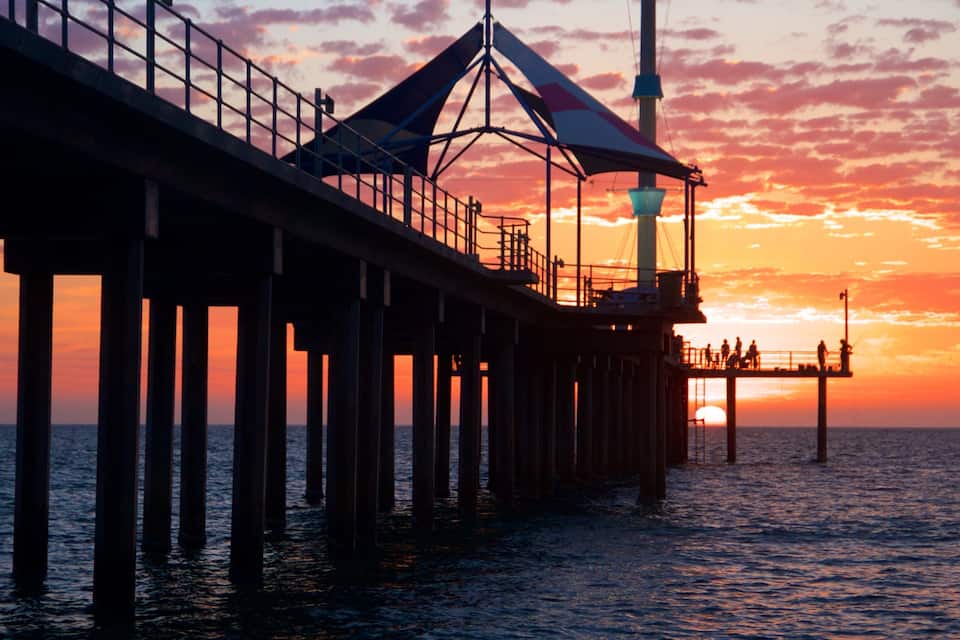A pier extending into the water at sunset with a colorful sky.