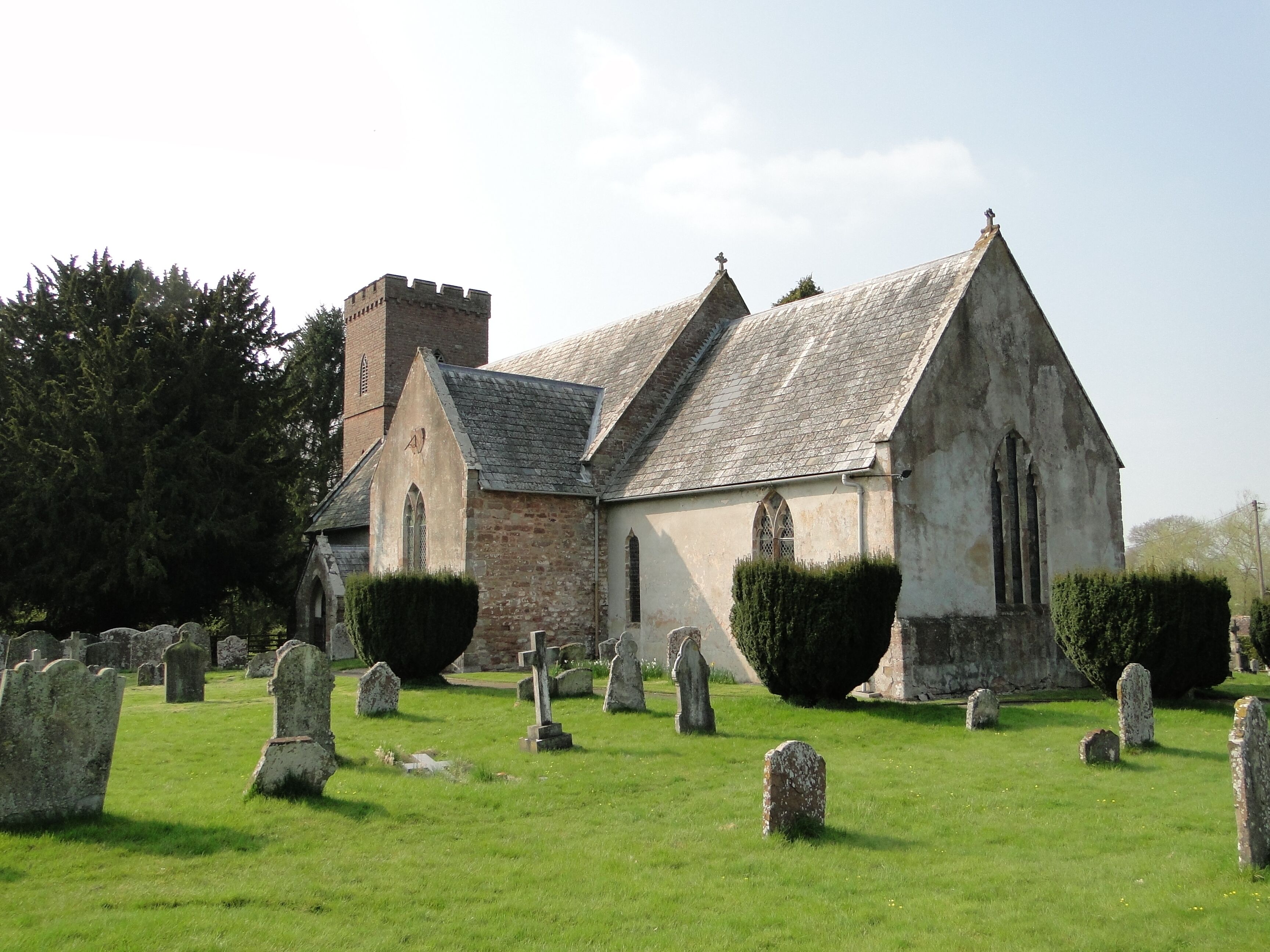 A church with a stone tower and a graveyard.