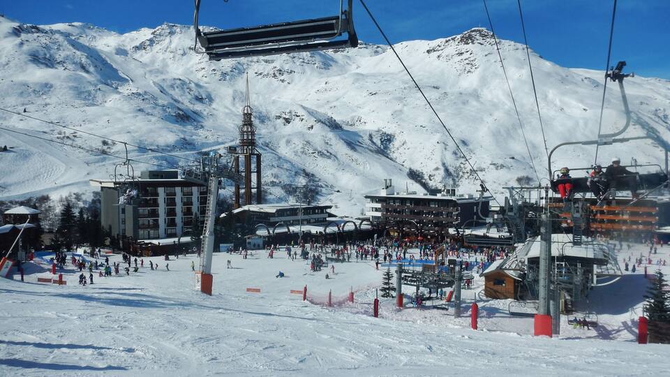 A ski resort with a chairlift, snow-covered slopes, and buildings.