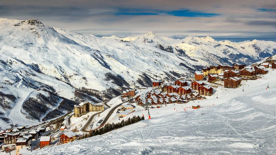 A snow-covered mountain town with ski slopes and buildings.