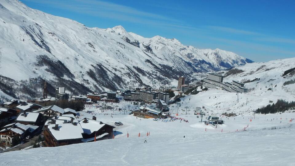 A snow-covered mountain village with ski slopes and buildings.