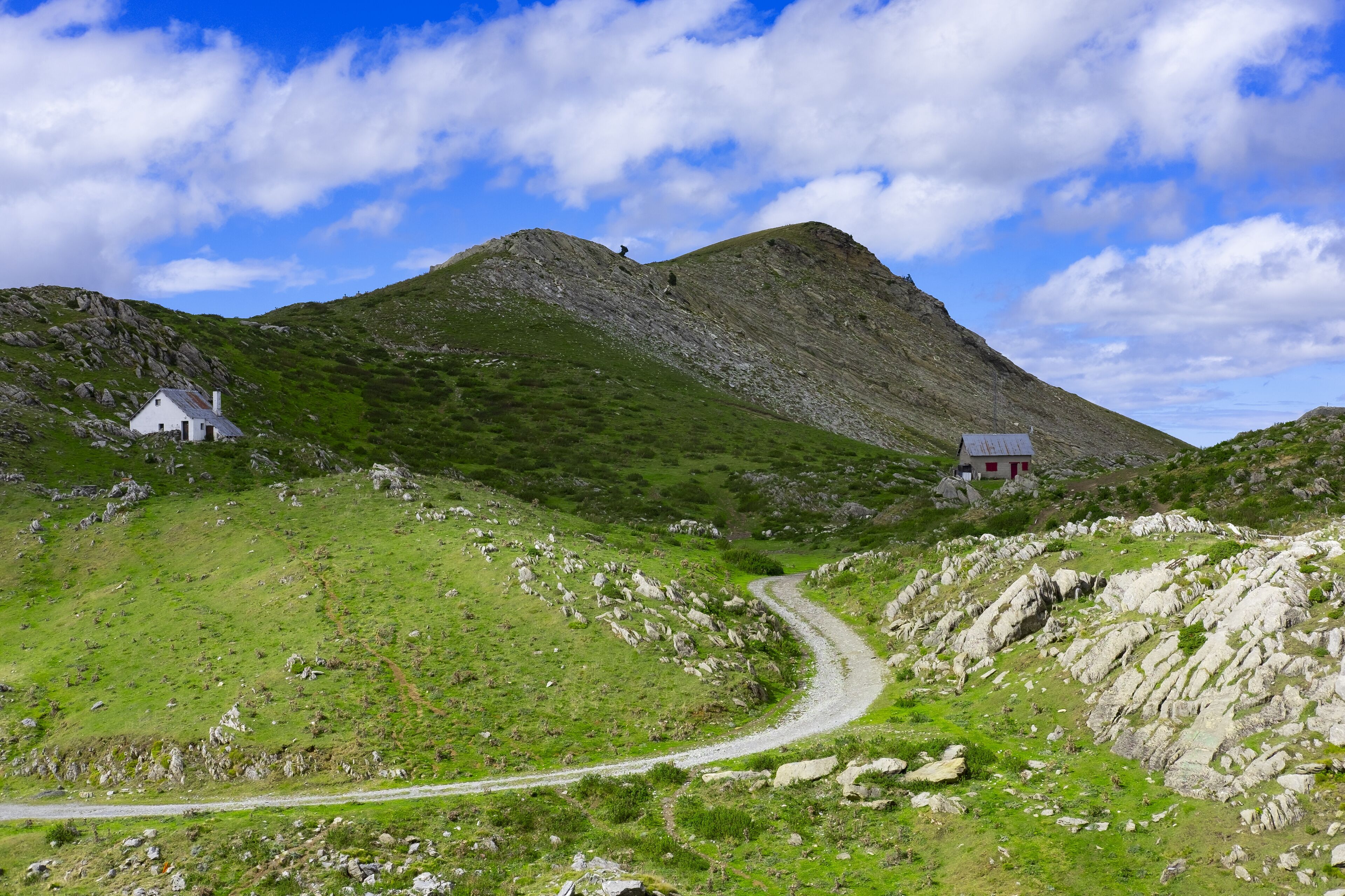 A winding mountain road, rocky terrain, and two white houses.