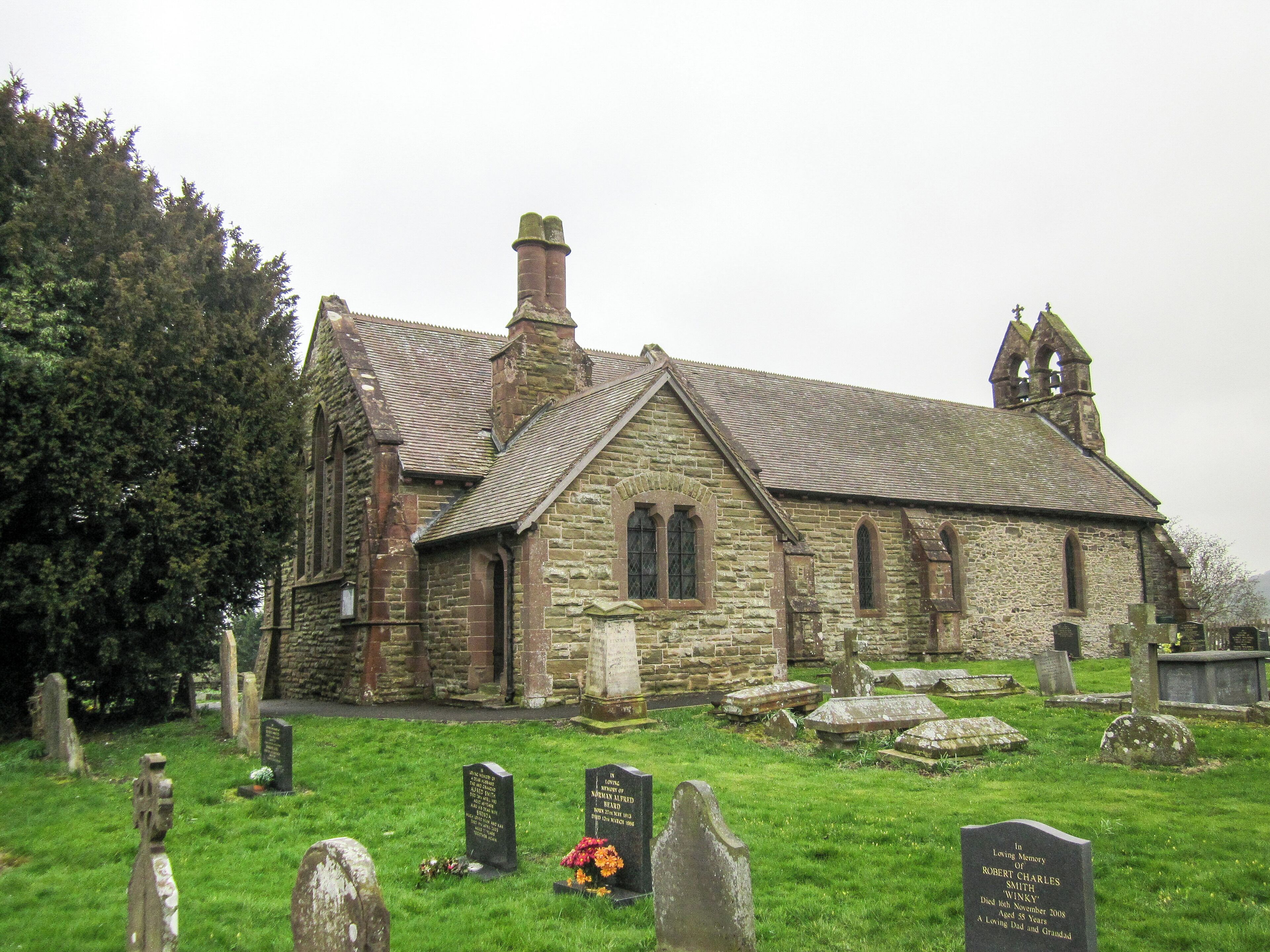 A stone church with a grassy cemetery in front.