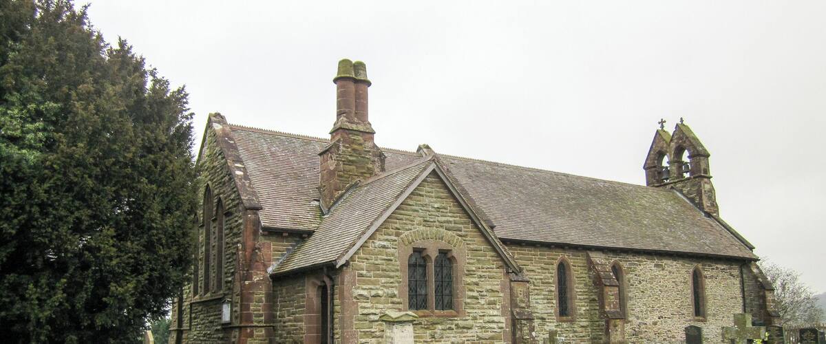 A stone church with a grassy cemetery in front.