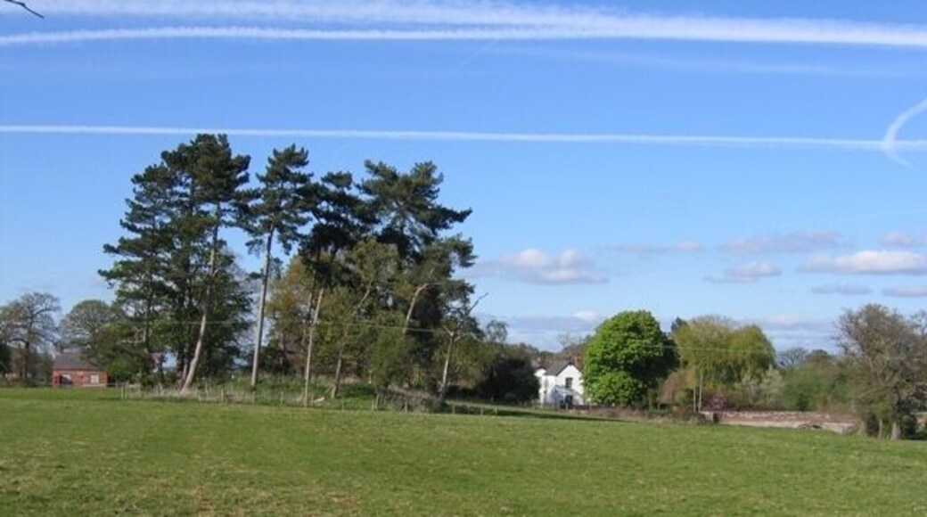Footpath in Coddington This footpath, from by the village pond in Coddington, leads directly to the old rectory, which is the white house. On the far left is the old school, now the village hall, and the clump of trees in the middle of the field is recorded as a 'mound' on modern maps, and a 'Tumulus' on the 1882 O.S. map. On the right of the photo the old sandstone bridge carries the road to Aldersey over Coddington Brook. St Mary's Church is almost invisible behind the clump of trees.