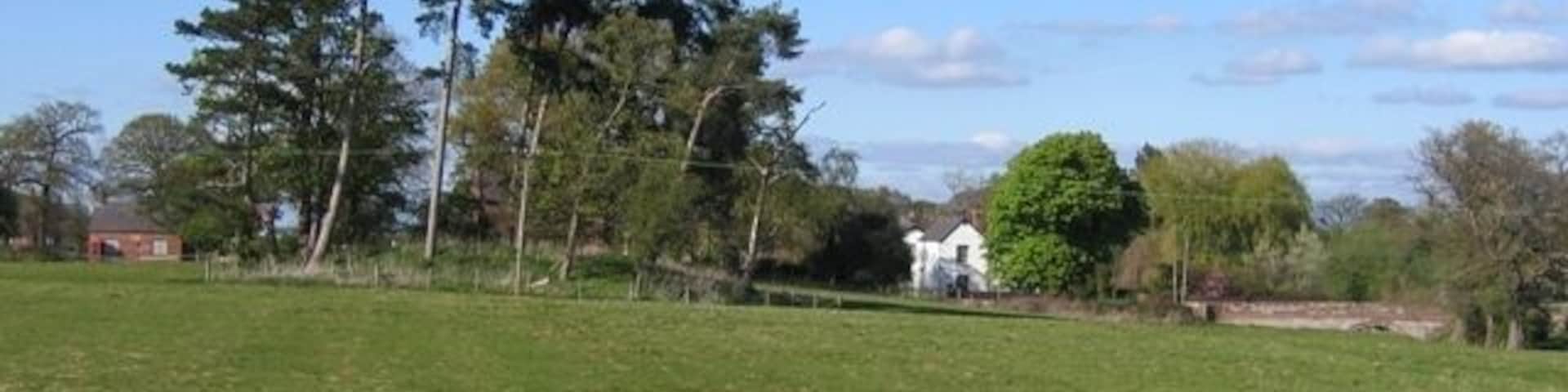 Footpath in Coddington This footpath, from by the village pond in Coddington, leads directly to the old rectory, which is the white house. On the far left is the old school, now the village hall, and the clump of trees in the middle of the field is recorded as a 'mound' on modern maps, and a 'Tumulus' on the 1882 O.S. map. On the right of the photo the old sandstone bridge carries the road to Aldersey over Coddington Brook. St Mary's Church is almost invisible behind the clump of trees.