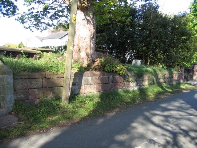 Graveyard Wall at Coddington St Mary. Viewed from Aldersey lane, this section of the graveyard wall runs between the church steps on the left, see 414565, and the gate to the old rectory on the right. About halfway along, between the wooden pole and the rectory gate, there is an inscribed stone with the name of at least one church warden, and the date 1748. This stone would seem to date the wall. Also see 414583 .