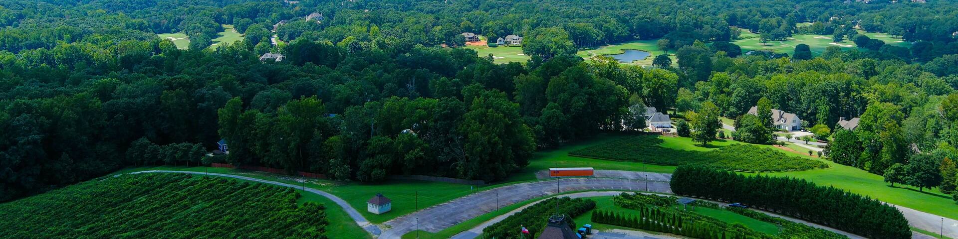 A lush green landscape with a golf course, a winding road, and scattered houses.