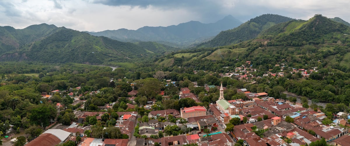 A town nestled in a valley surrounded by lush green mountains.