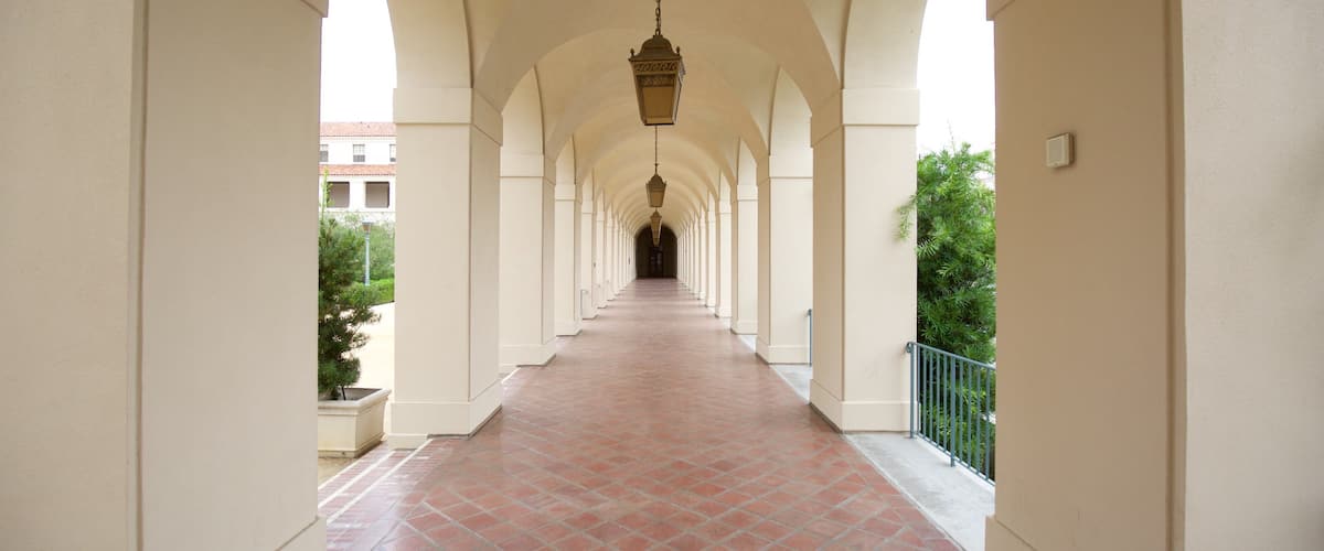 A corridor with arches, a hanging lantern, and a tiled floor.