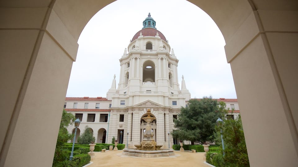 A grand building with a large dome and bell tower, surrounded by a well-maintained garden and a clear sky.