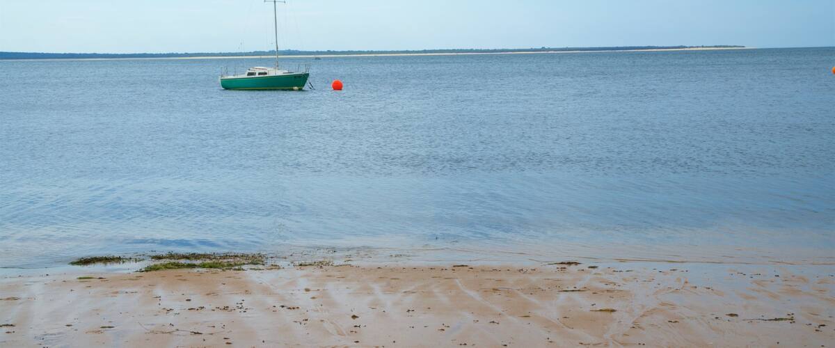 A calm sea with a green boat anchored near the shore.