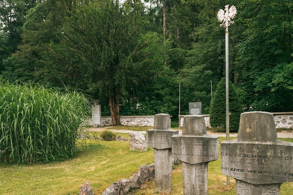 Ein Friedhof mit Steinkreuzen und einem großen Baum im Hintergrund.