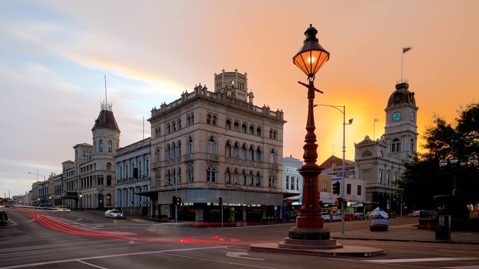 A historic building with ornate architecture and a clock tower, set against a sunset sky.