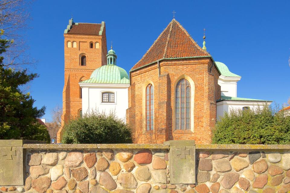 A church with a brick tower and a green dome.