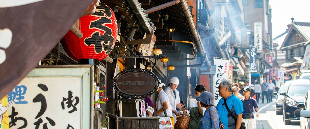 A busy street with traditional Japanese signage and a red lantern.