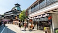A street with traditional Japanese architecture, including a pagoda and wooden buildings with signage.
