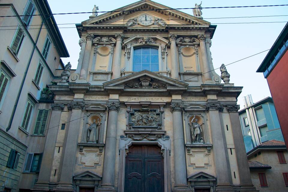 A historic building with a central dome, ornate columns, and statues.