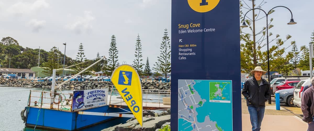 Eden Wharf showing a bay or harbor and signage as well as an individual male