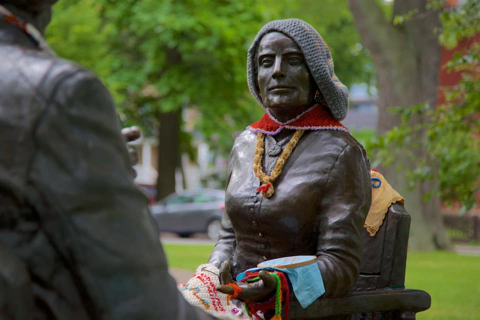 En statue af en person, der sidder på en bænk i en park.