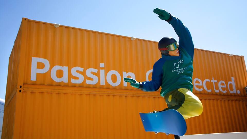 A snowboarder performing a trick in front of a shipping container with the word "Passionate" on it.
