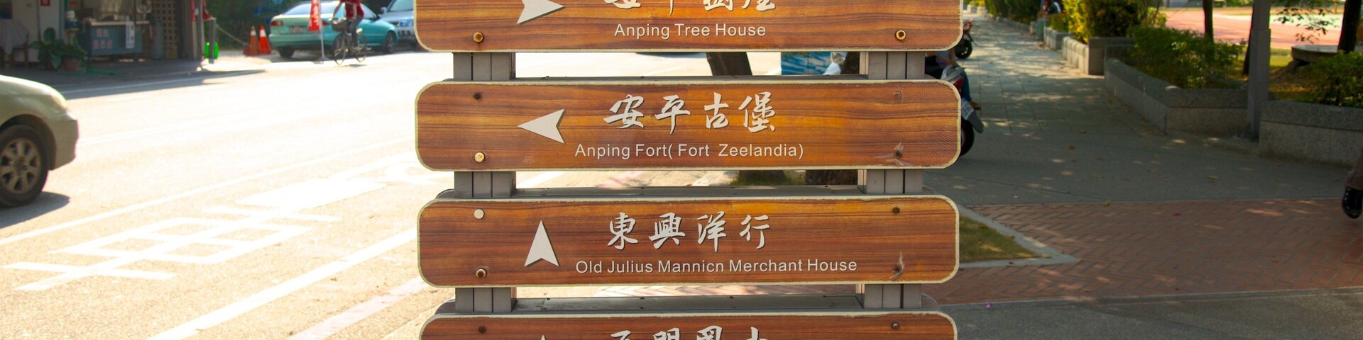 Un cartel de madera con indicaciones a varios puntos de referencia locales, como la Casa Comercial Old Tait & Co., la Casa del Árbol de Anping, la Fortaleza de Anping, la Casa Comercial Old Julius Mannic, la Escuela Primaria Simen y la Casa Sio.
