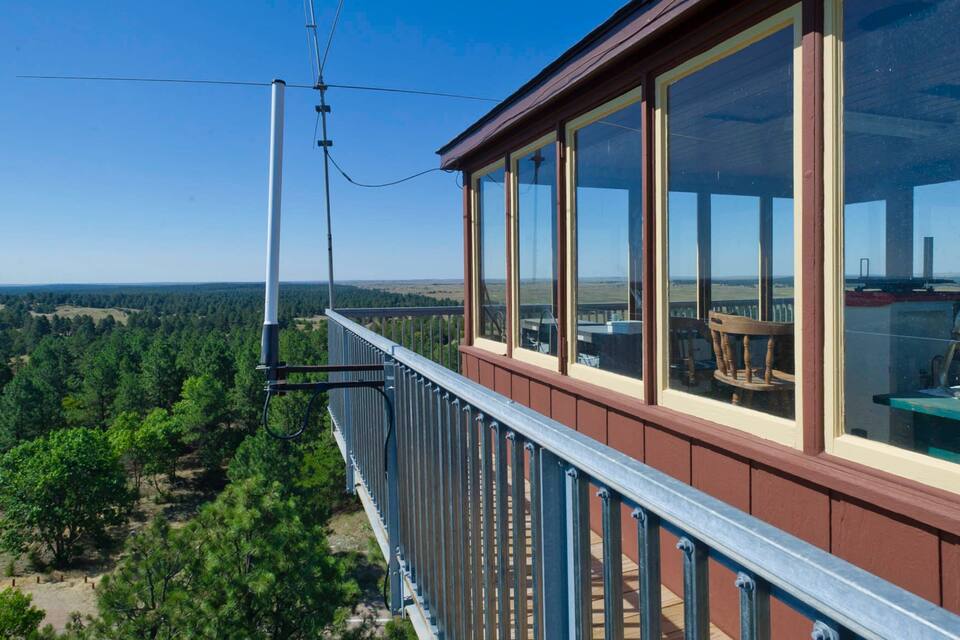 Un balcon en bois doté de grandes fenêtres donnant sur un paysage boisé.