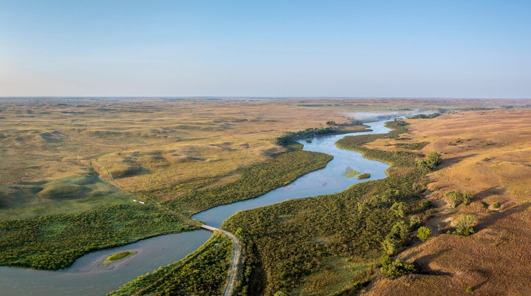A river winding through a landscape with patches of greenery and dry grass.