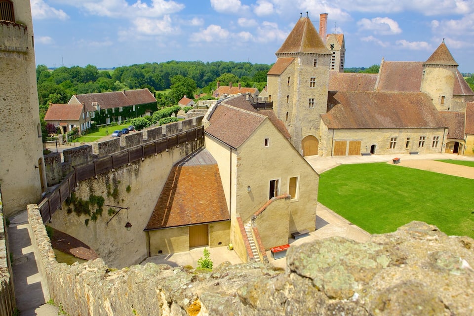 A medieval castle with a moat, stone walls, and a grassy courtyard.