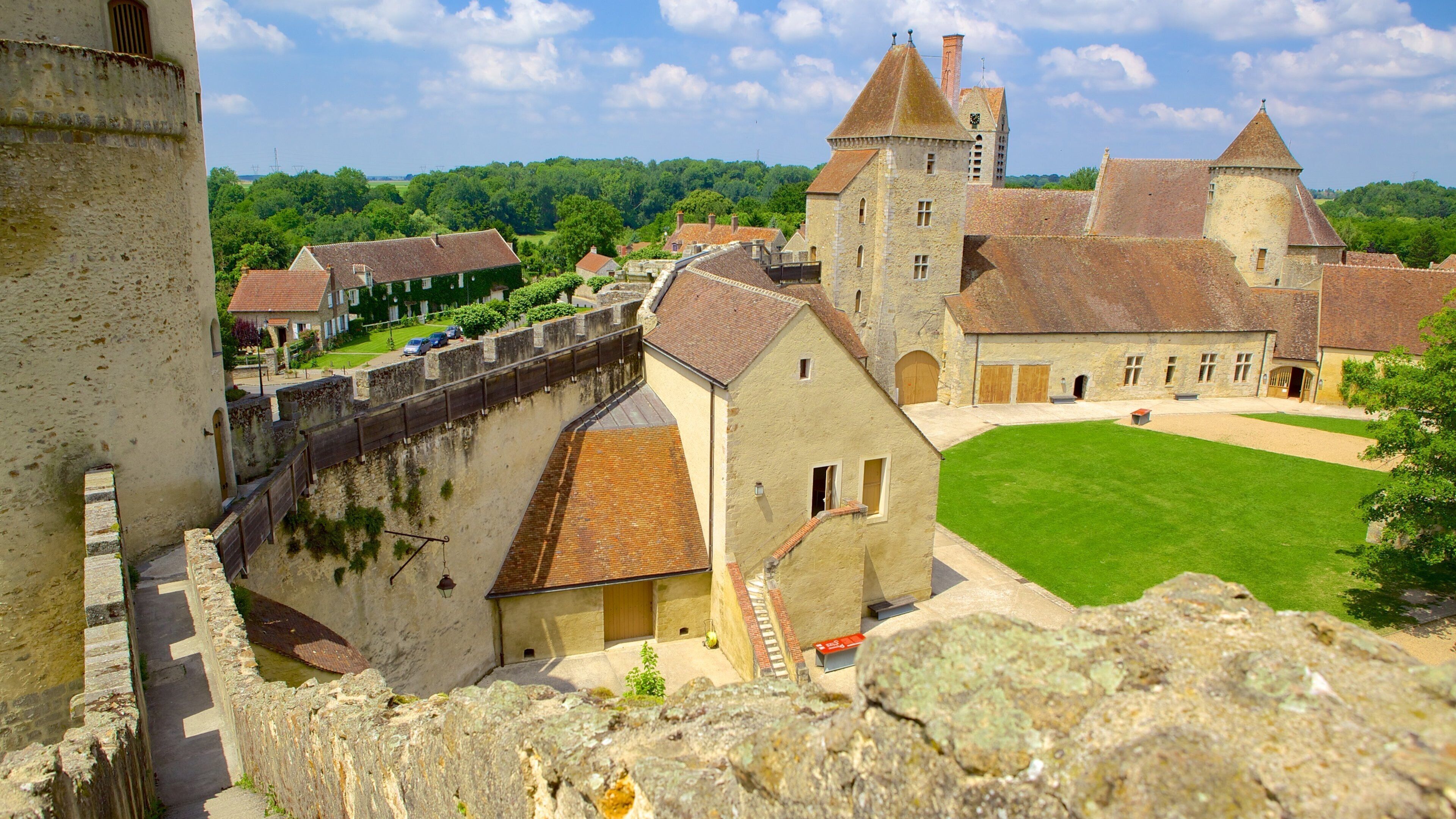 A medieval castle with a moat, stone walls, and a grassy courtyard.