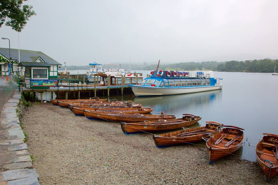 A lakeside dock with wooden boats and a large ferry.