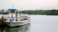 A boat named Miss Lakeland II docked at a pier with a forested shoreline in the background.