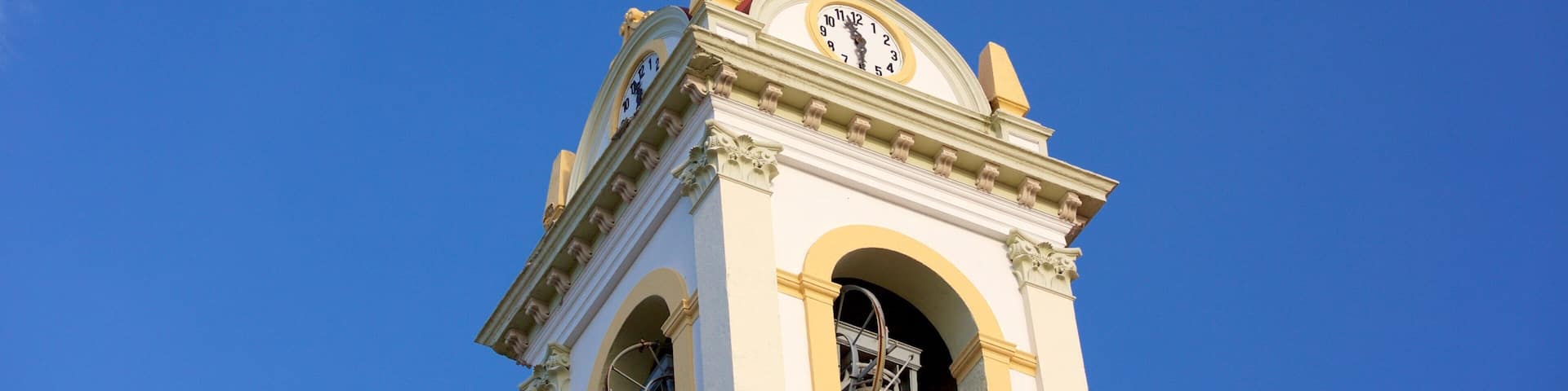 A clock tower with a red roof and a weather vane.