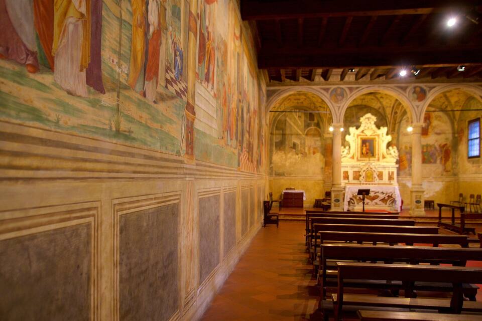 L’intérieur d’une église, avec ses bancs en bois, son autel central et ses fresques colorées sur les murs.