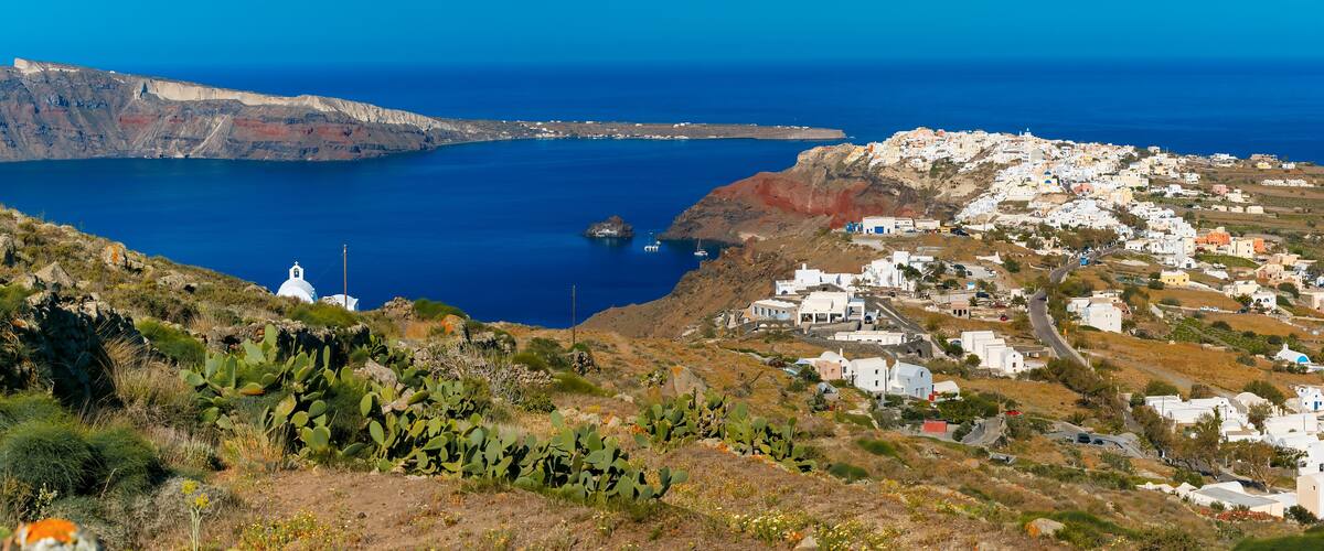 Aerial panoramic view of Oia or Ia and Finikia on the island Santorini, white houses, windmills and church with blue domes, Greece