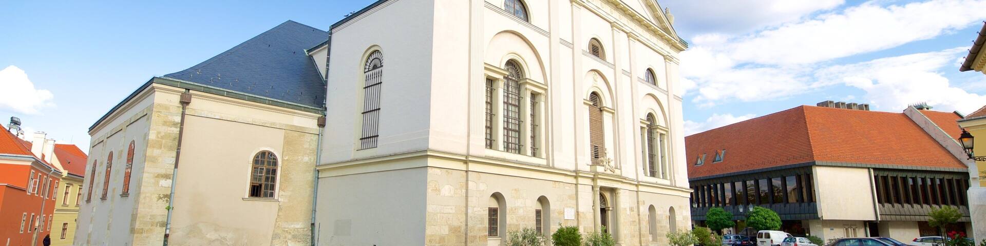 A historic church with a clock tower, surrounded by cobblestone streets and modern buildings.