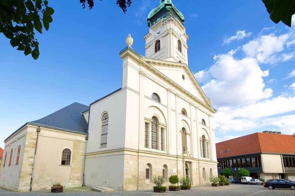 A historic church with a clock tower, surrounded by cobblestone streets and modern buildings.