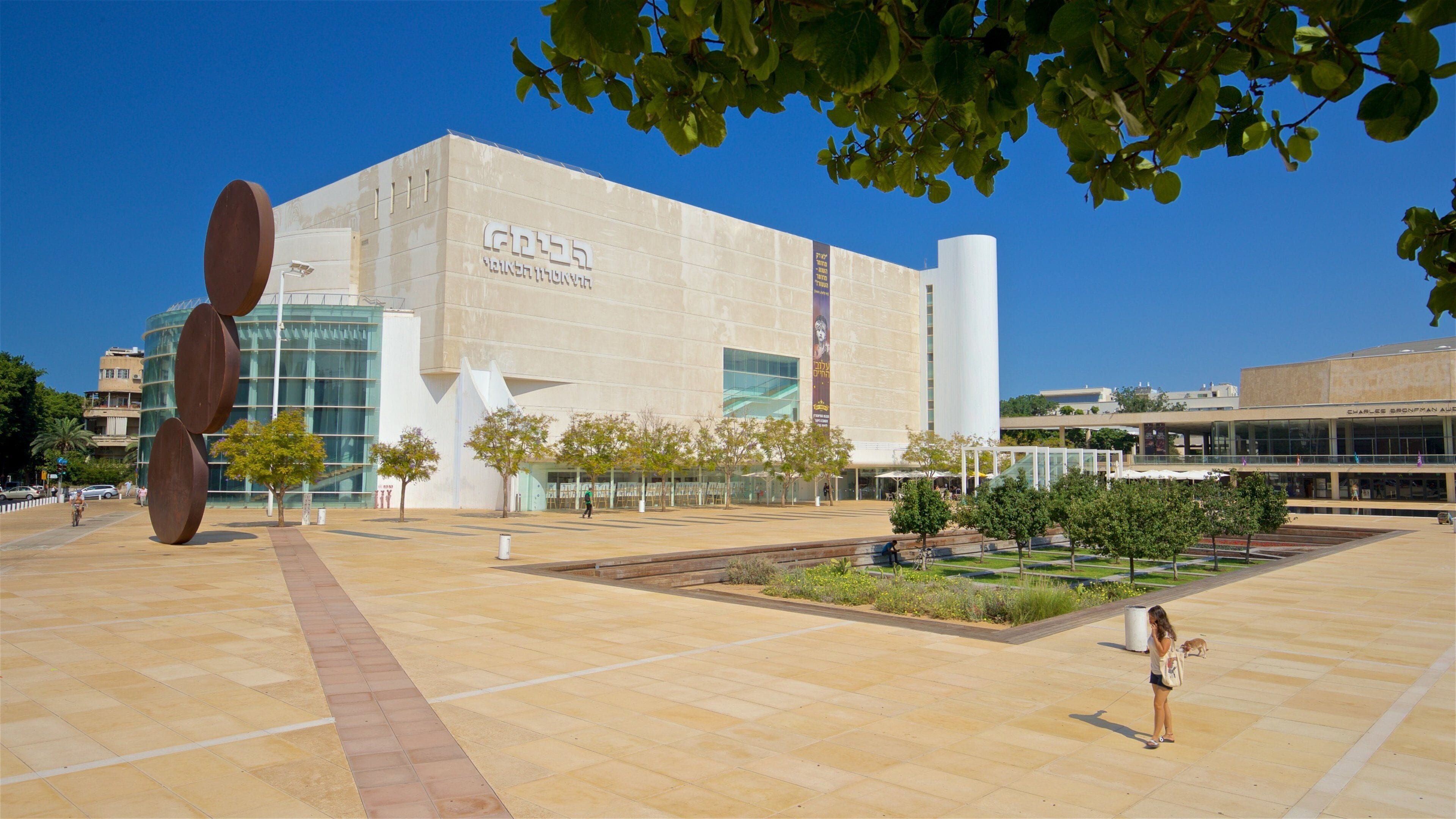 A modern building with a large glass facade and a prominent sculpture in the foreground.