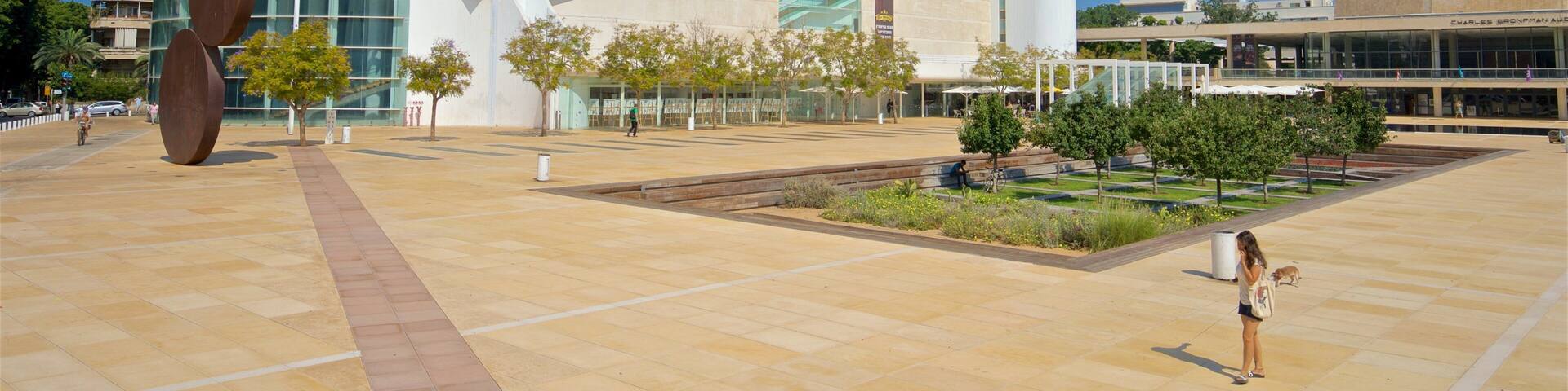 A modern building with a large glass facade and a prominent sculpture in the foreground.