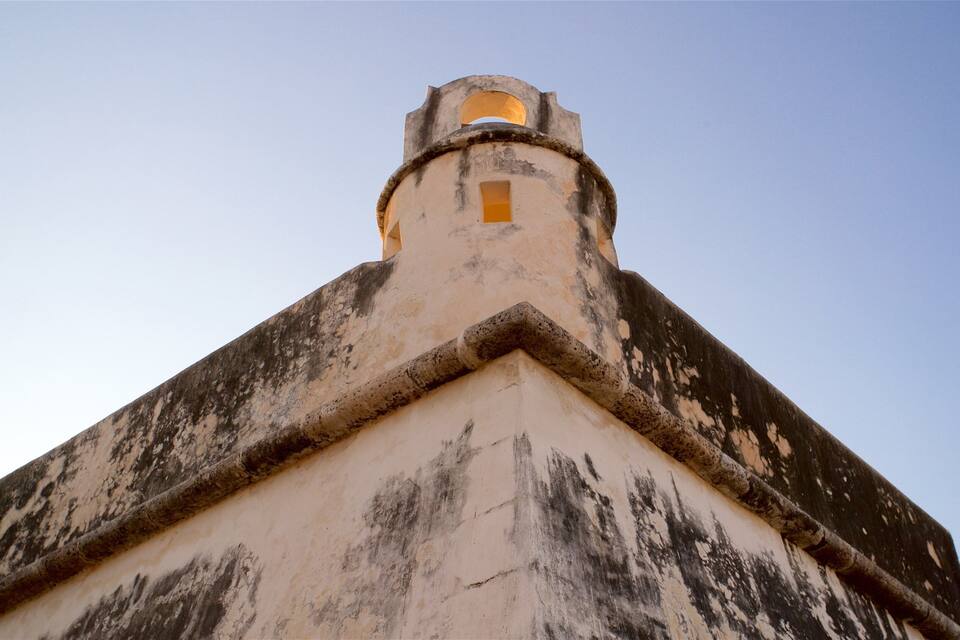 A weathered building with a pointed roof and a small window.