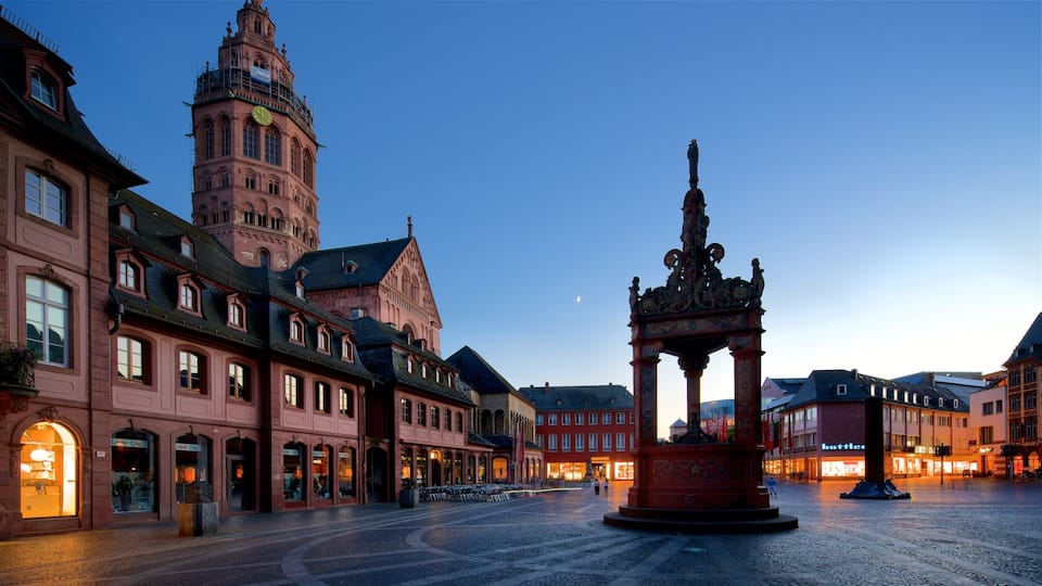 A historic square with a prominent clock tower and a decorative fountain.