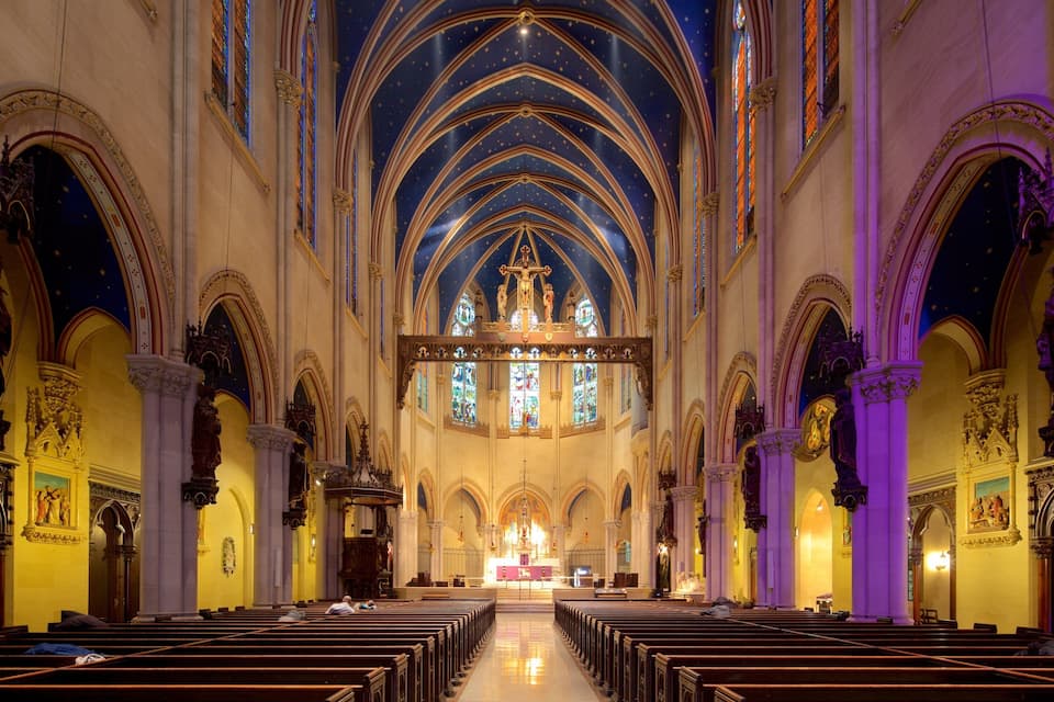 Ein Dominneres mit hohen Gewölbedecken, Buntglasfenstern und Reihen von Kirchenbänken.