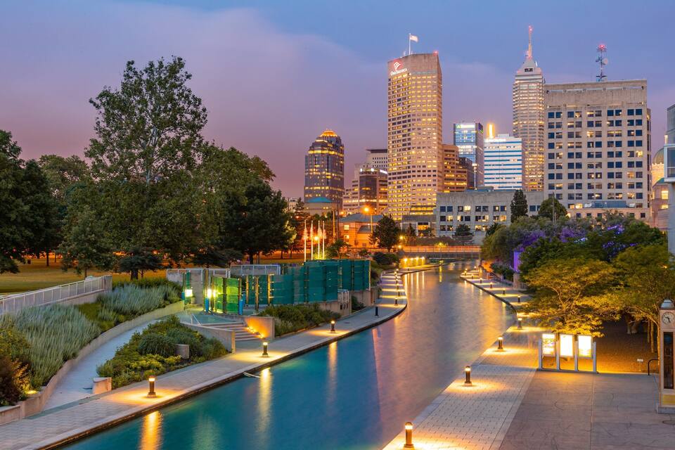 Vista urbana con un río, edificios modernos y una torre del reloj.
