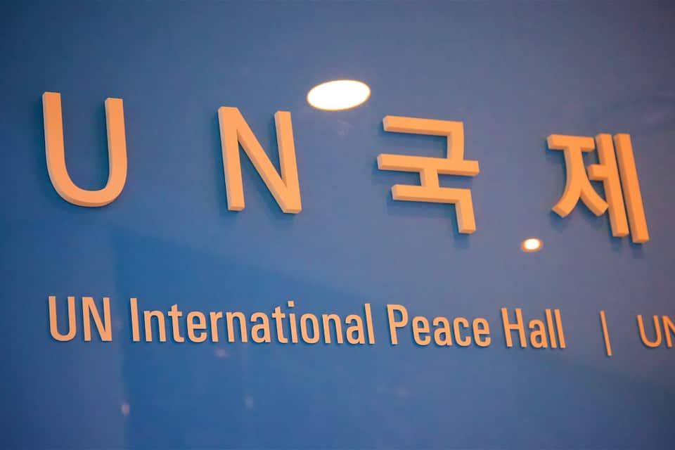 Een bord met de tekst 'UN International Peace Hall' en 'UN' in het Engels en een andere taal.