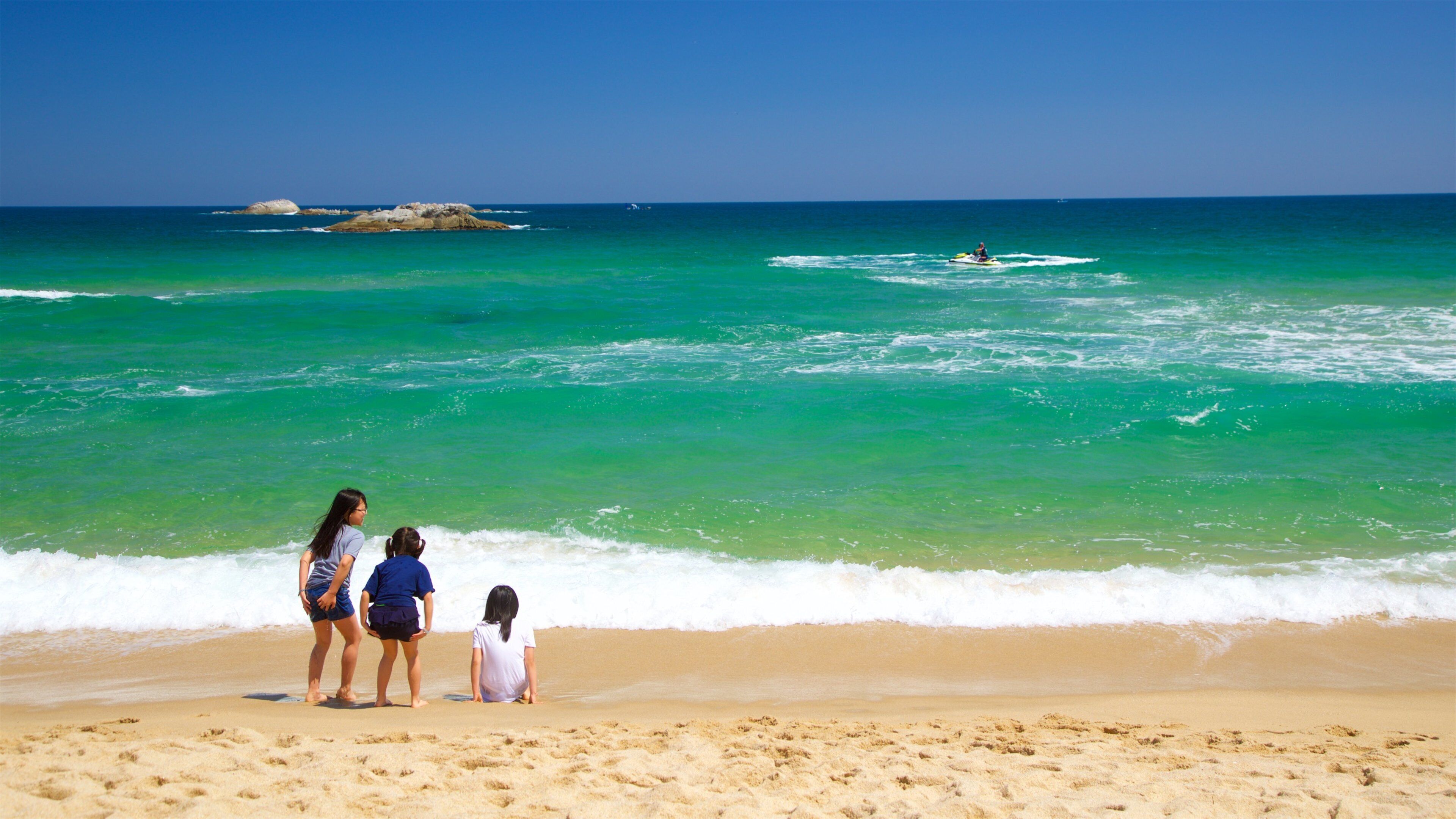 Gyeongpo Beach featuring a sandy beach and general coastal views as well as a small group of people