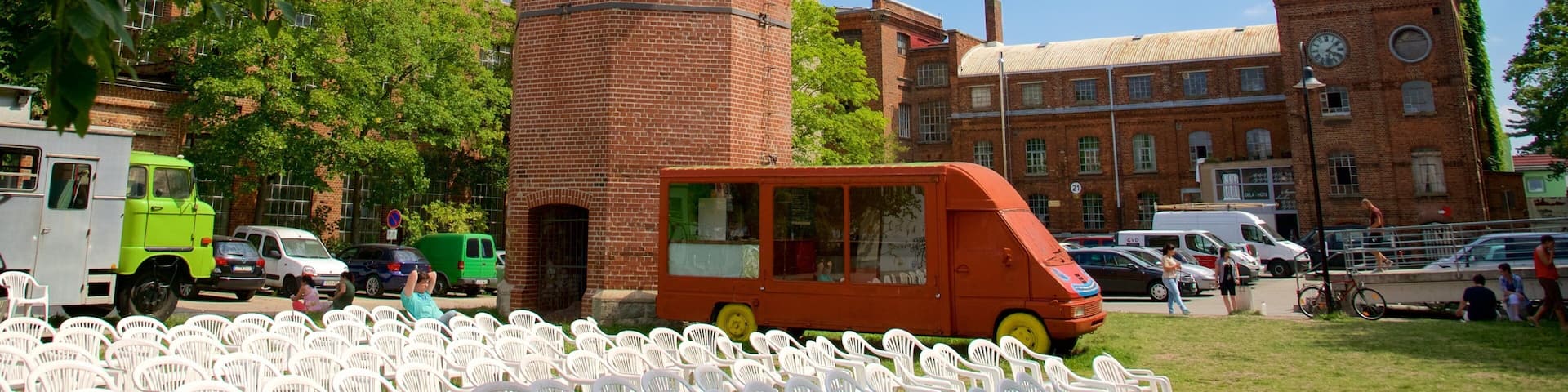 A brick tower, a green bus, and a building with a clock.