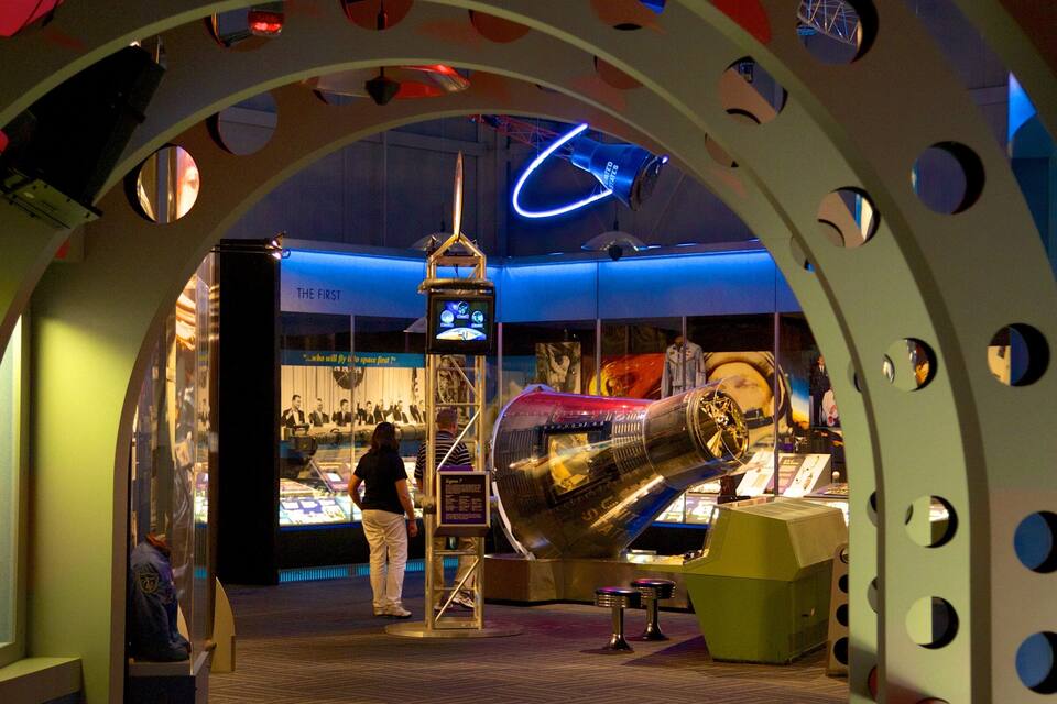 Una exposició de museu amb un gran model de transbordador espacial, un rellotge de neó i plafons informatius.